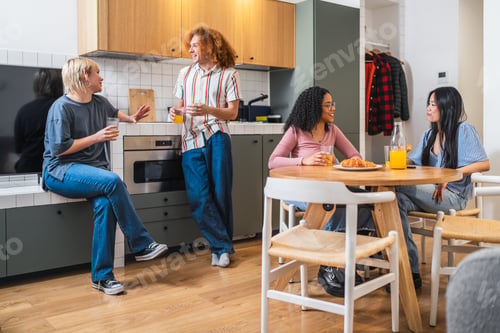 Preview: Young multiethnic friends enjoying breakfast and conversation in modern kitchen