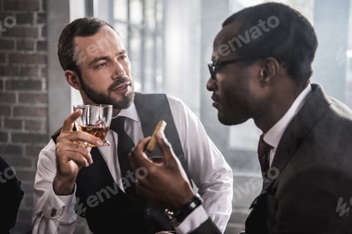 Preview: Two confident men with cigar and glass of alcohol beverage talking