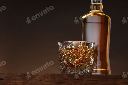 Vista previa: Whisky en vaso y botella sobre mesa de madera sobre fondo marrón, espacio para texto
