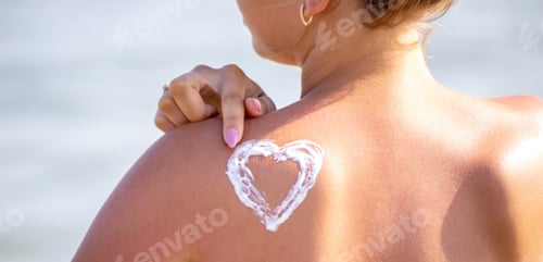 Preview: painted heart on the girl's back with sun cream.