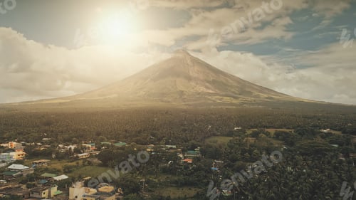 Preview: Aerial volcano erupt at sunlight closeup. Sun cityscape of rural town at green volcano valley