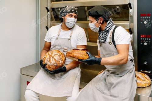 Preview: two happy latino bakers showing how they made a loaf of wheat bread in the bread oven