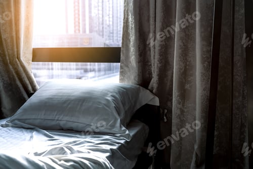 Preview: White comfort bed and soft pillow in modern bedroom. Bed near window and curtain at hotel