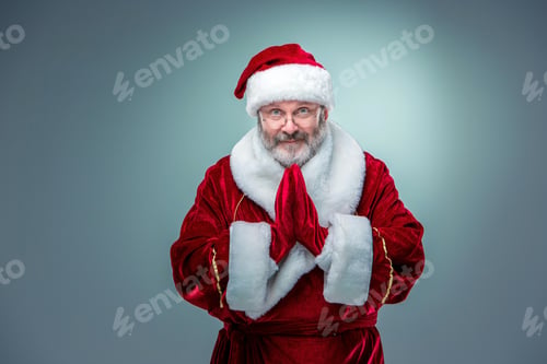 Preview: A Happy, Smiling Santa Claus In Glasses With Hands In Thai Greeting On A Blue Background