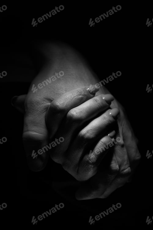 Vista previa: Vertical romantic shot of a couple holding hands on a black background