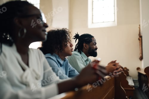Preview: Family praying together in church pew holding hands