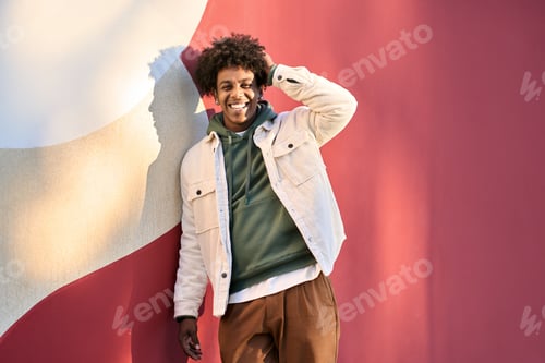 Preview: Young happy African American teen guy standing at red wall. Portrait