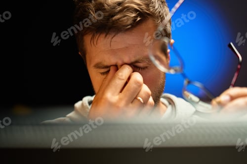Preview: Tired man rubbing eyes while holding glasses
