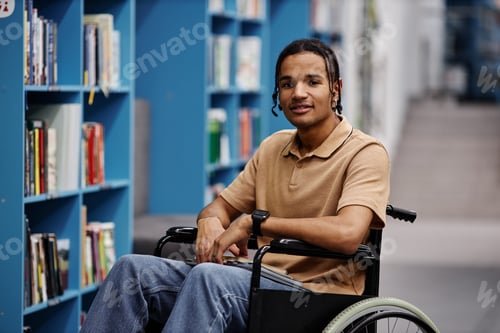 Preview: Black young man with disability in library at modern college