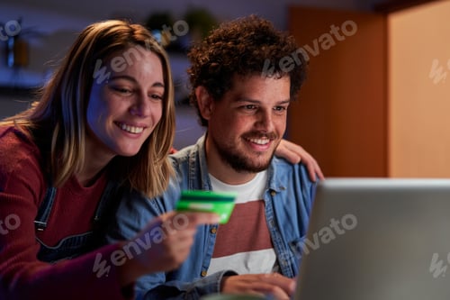 Preview: Young couple doing online shopping from home using a laptop and a credit card.