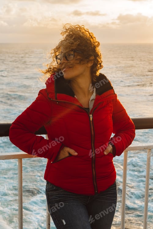 Preview: Cruise ship vacation woman enjoying sunset on travel at sea. Traveler happy woman in red jacket