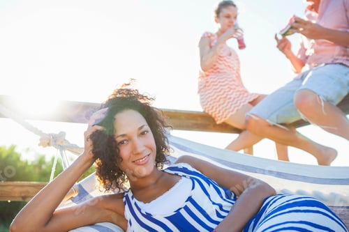 Preview: Young woman smiling on hammock, portrait
