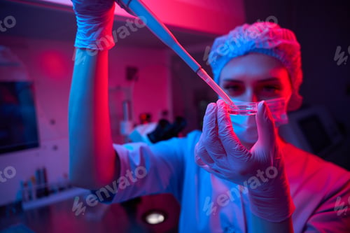 Preview: Lab technician handles cryopreservation sample under pink and blue lighting