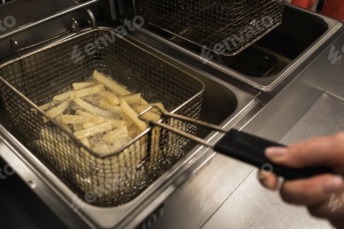 Preview: Crispy french fries being fried in a commercial kitchen during a busy lunchtime at a popular eatery