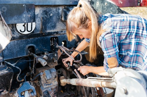 Preview: Woman Repairs Tractor Engine in Rural Setting
