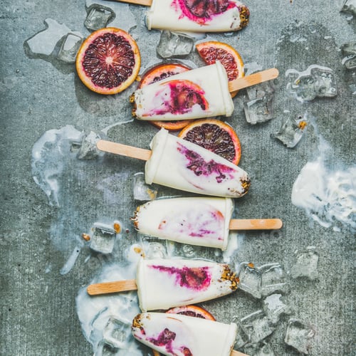 Preview: Red orange, yogurt, granola popsicles on ice cubes, square crop