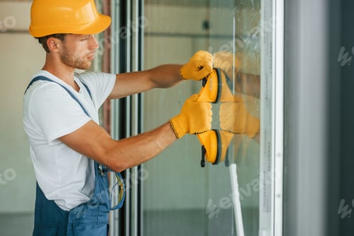 Preview: Side view. Young man working in uniform at construction at daytime