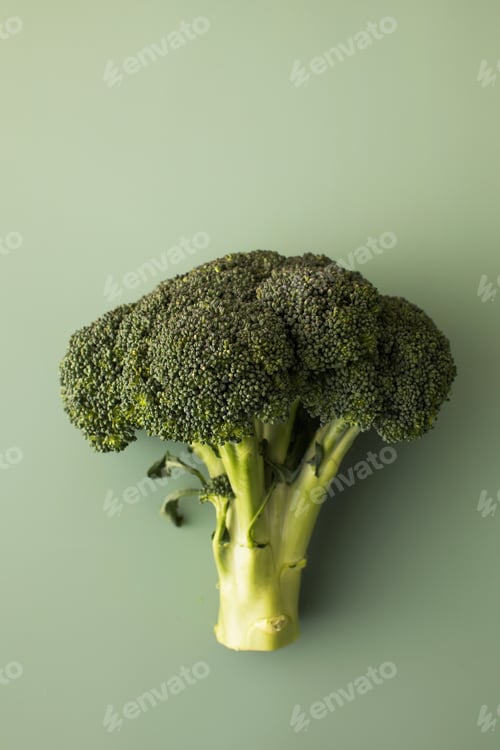 Preview: Fresh raw whole broccoli on a green background. Vegetarianism, healthy eating. Flatlay