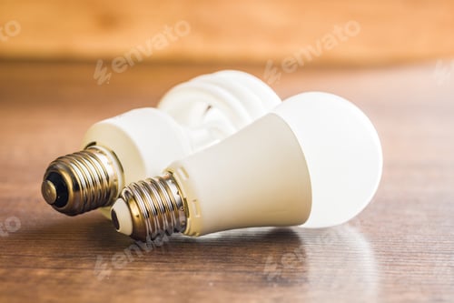 Preview: Energy saving light bulb . Fluorescent and led Lightbulb on wooden table.
