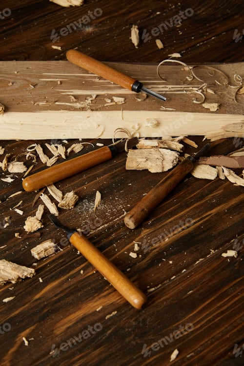 Preview: closeup shot of chisels and wooden pieces on brown table