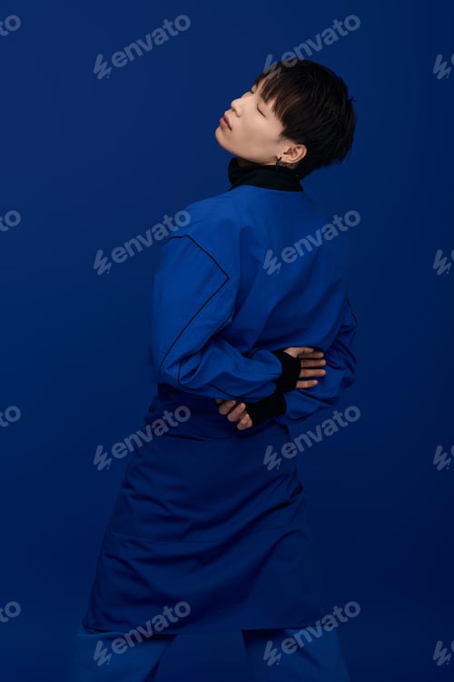 Preview: Young handsome Asian man poses stylishly against a blue backdrop for artistic expression