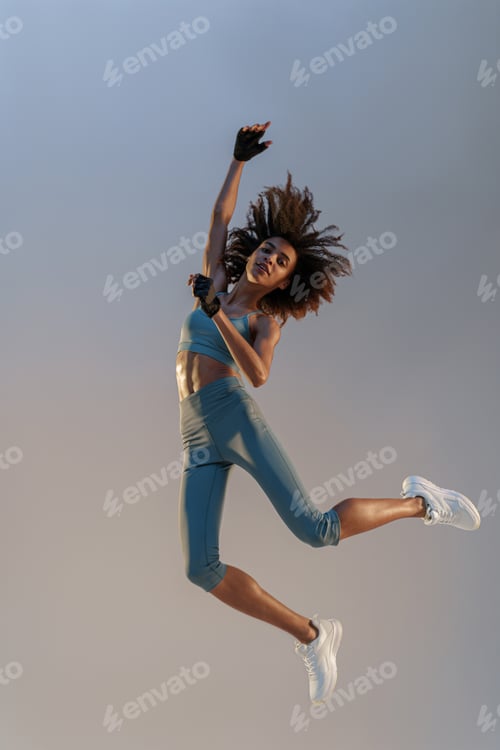Preview: Active sporty woman in sportswear jumping on studio background. Sport and healthy lifestyle