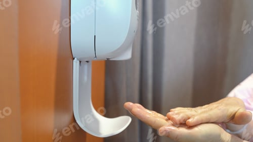 Preview: Senior patient woman washing her hand from automatic hand sanitizer in hospital