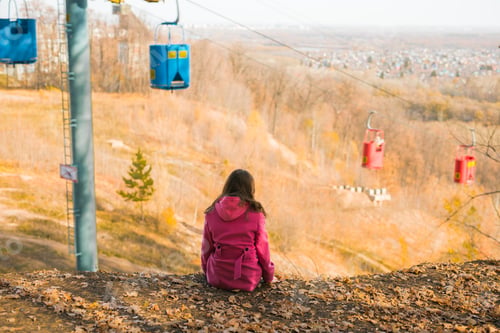 Preview: Back view of a girl woman resting on autumn park in fall season and look at the cable car