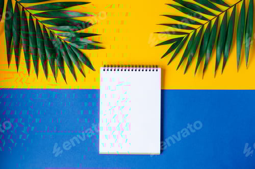 Preview: A blank spiral notebook on a yellow background with green palm leaves.