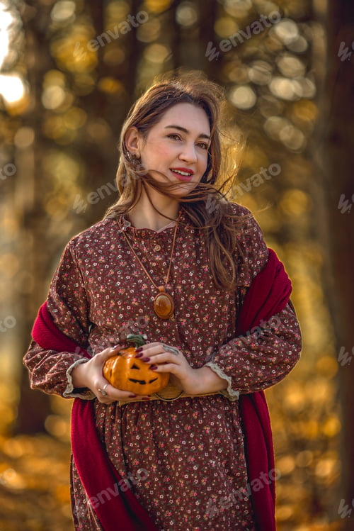 Preview: Young woman walking in the park on Halloween. Golden autumn