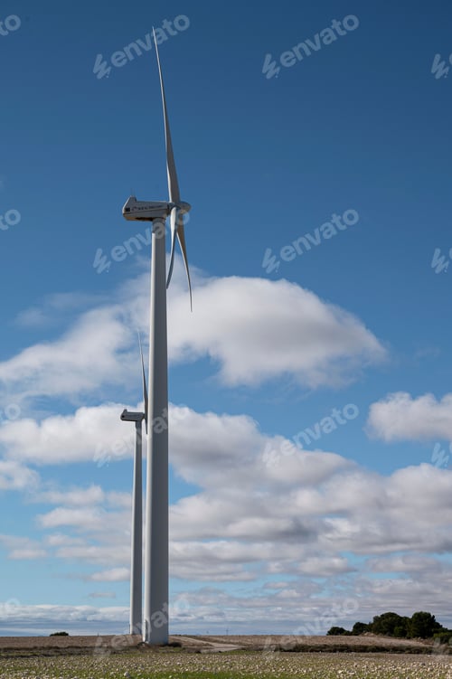 Preview: Vertical shot of the wind turbines against blue cloudy sky