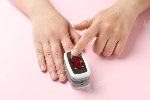 Preview: Woman using fingertip pulse oximeter on pink background, closeup