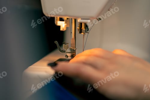 Preview: close-up in a sewing workshop on a machine the seamstress master makes cut on a blue fabric