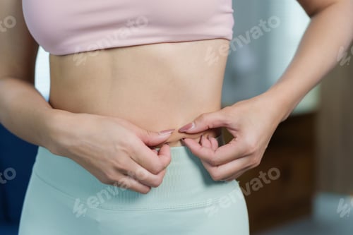 Preview: Woman pinching belly fat, checking subcutaneous body fat, weight loss concept