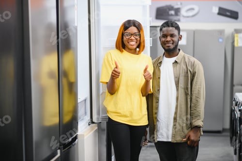 Preview: Young african american man and woman are choosing a fridge in an appliance store.
