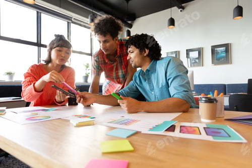 Preview: Creative multiracial male and female design professionals discussing at table in office