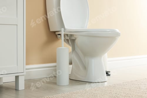 Preview: Toilet bowl and brush near beige wall in restroom