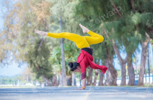 Preview: Asian young healthy woman posing practice bird of paradise yoga on stone beach with blue cloud sky a