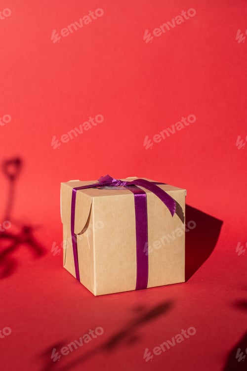 Preview: A craft gift box with a ribbon stands on a red background