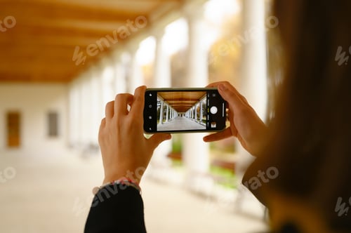 Preview: Woman's hands photographing the columns of a building with her smartphone