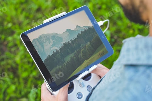 Preview: Young man flying drone on amazing mountain landscape. Man operating a drone with remote control