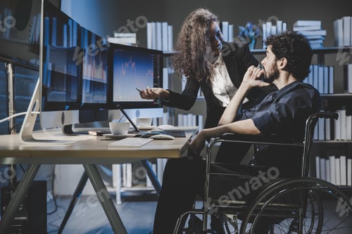 Preview: team brokers sit on wheelchair and look at stock market graph on monitor computer to analyze