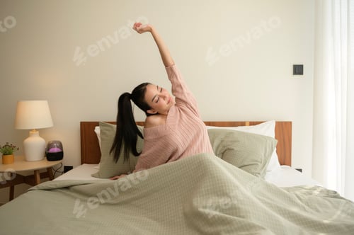 Preview: Young asian woman stretching in bed after Waking up in the Morning