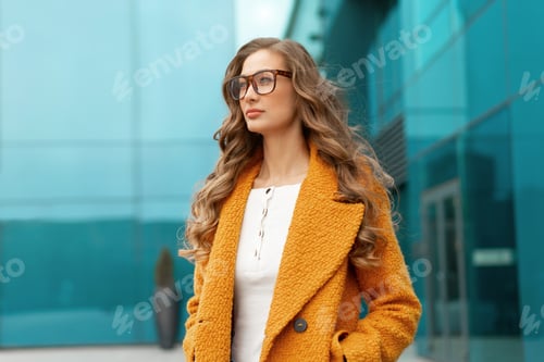 Preview: Business woman standing near corporative building outdoor dressed yellow stylish coat