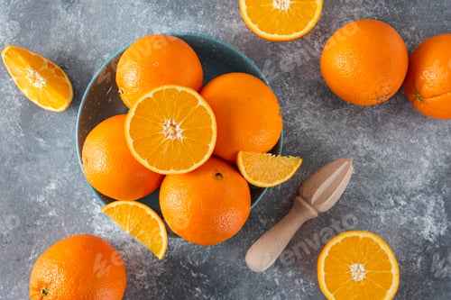 Preview: A bowl full of sliced and whole juicy orange fruits with wooden reamer