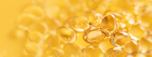Preview: Banner closeup of oil gel capsules on yellow background.