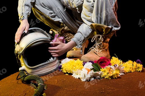 Preview: cropped view of astronaut in spacesuit with flowers and helmet sitting on mars