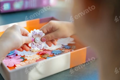 Preview: Small, colorful paper flowers in child hands, little girl creativing of 3D flowers. Child