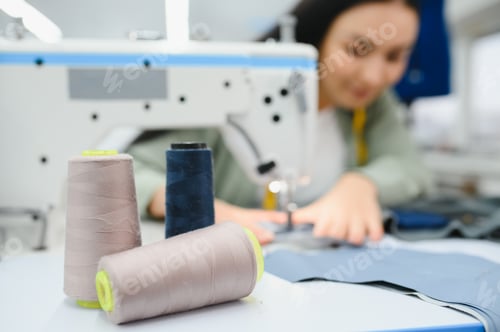 Preview: Young dressmaker woman sews clothes on working table.