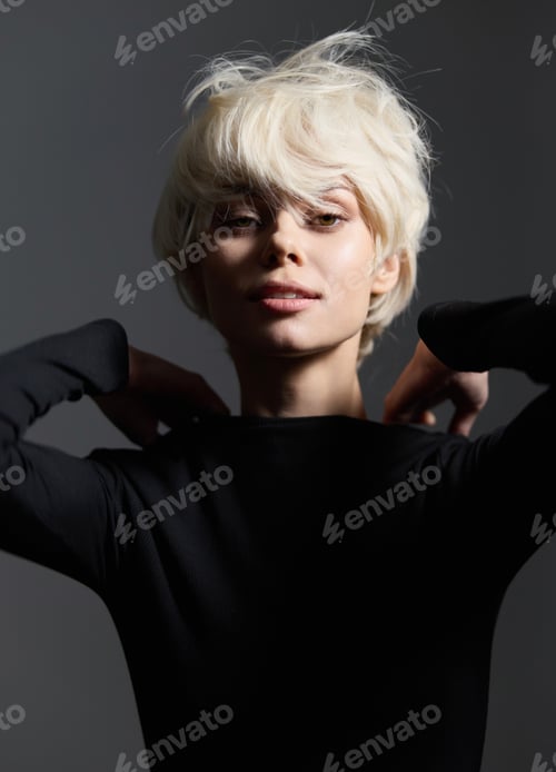 Preview: Elegant blonde woman with short hair, wearing a black top, poses with confidence against a dark